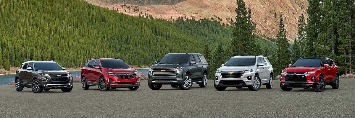 5 Chevrolet Vehicles outside by mountains and river